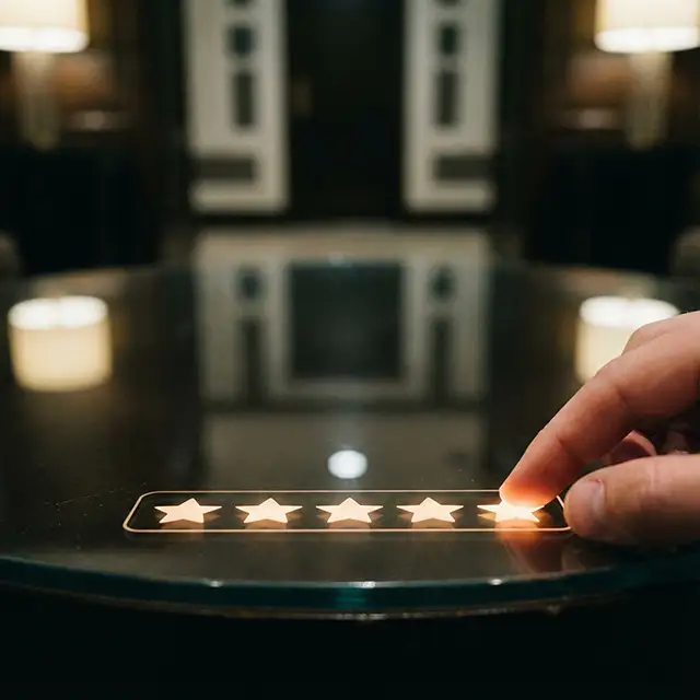 暗い反射面で輝く 5 つ星の評価で 5 番目の星に触れる手。
